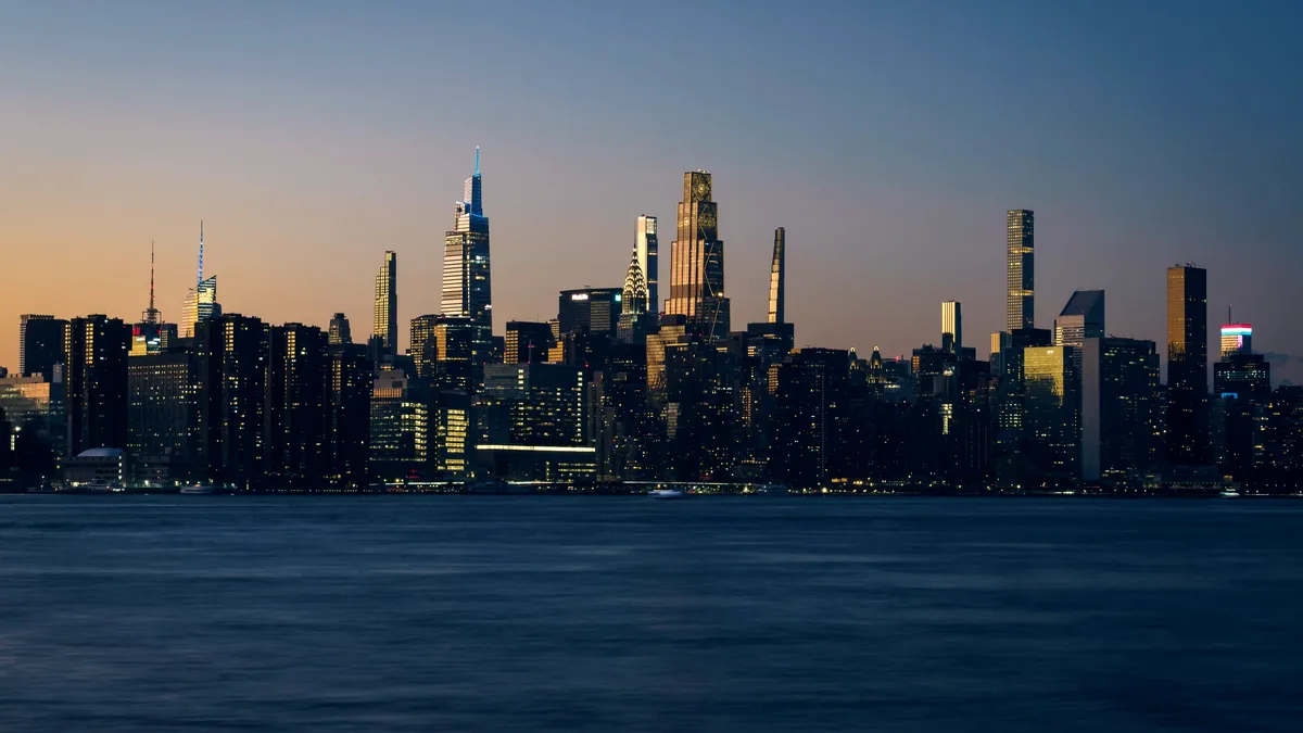 Horizonte de Nova York ao anoitecer, com prédios iluminados à beira d'água