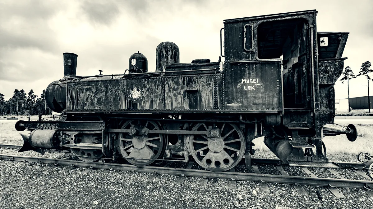 Locomotiva a vapor antiga e enferrujada parada sobre trilhos