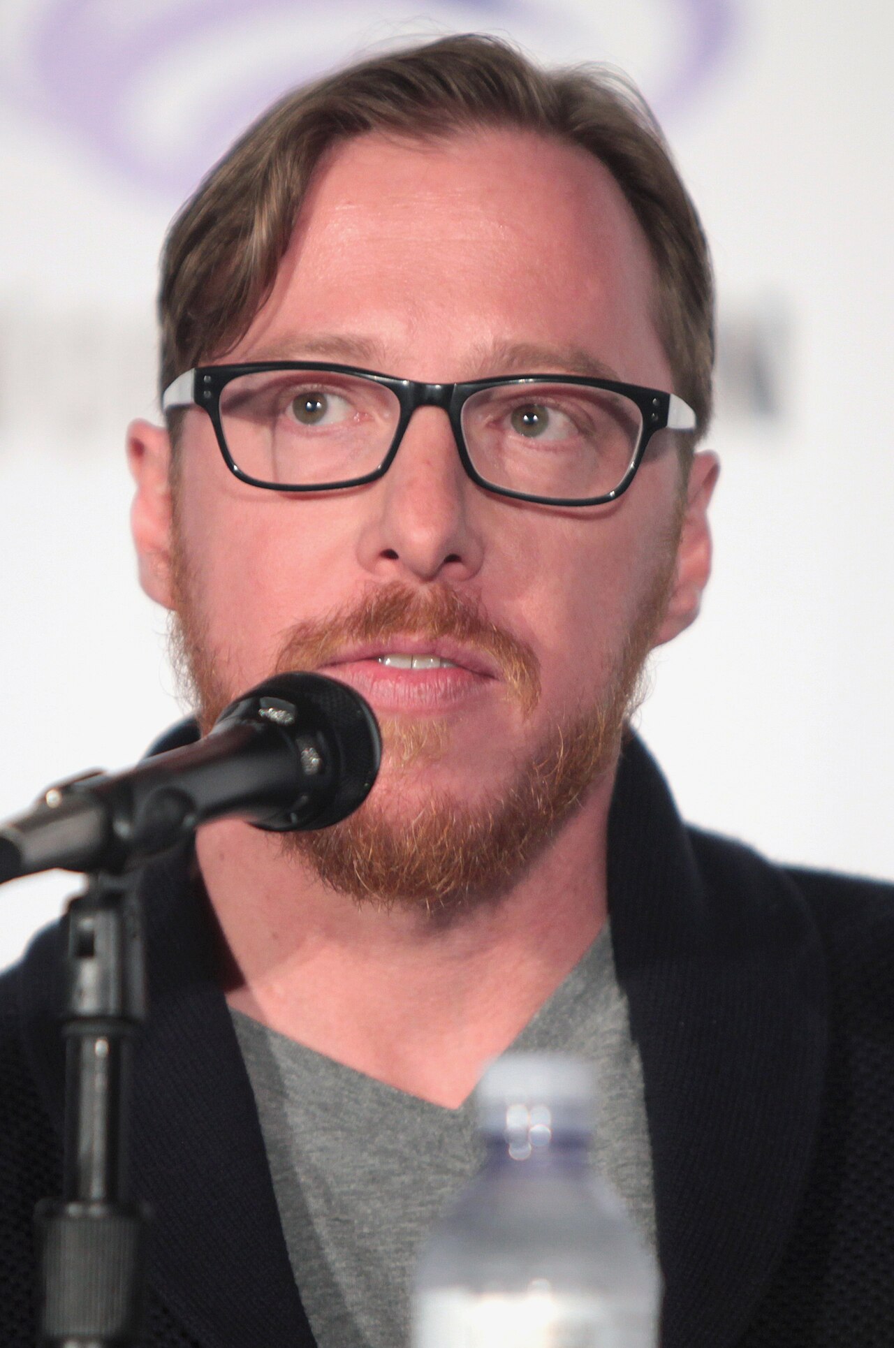 Blake Crouch, de camisa escura, fala ao microfone em um painel da WonderCon