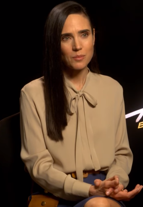 Jennifer Connelly, de cabelo escuro preso, sorri em uma entrevista