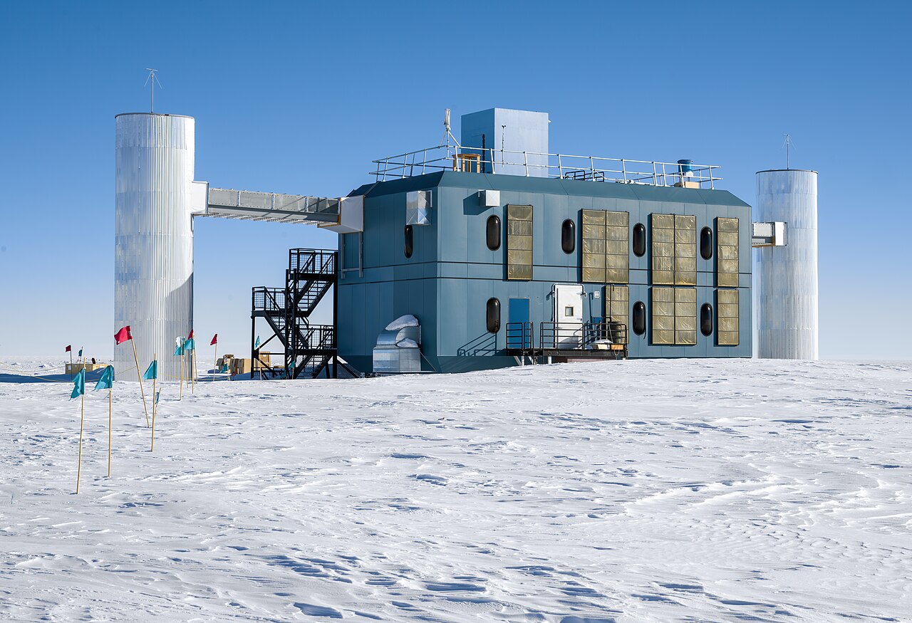 Prédio branco do laboratório IceCube no gelo da Antártida, sob céu azul