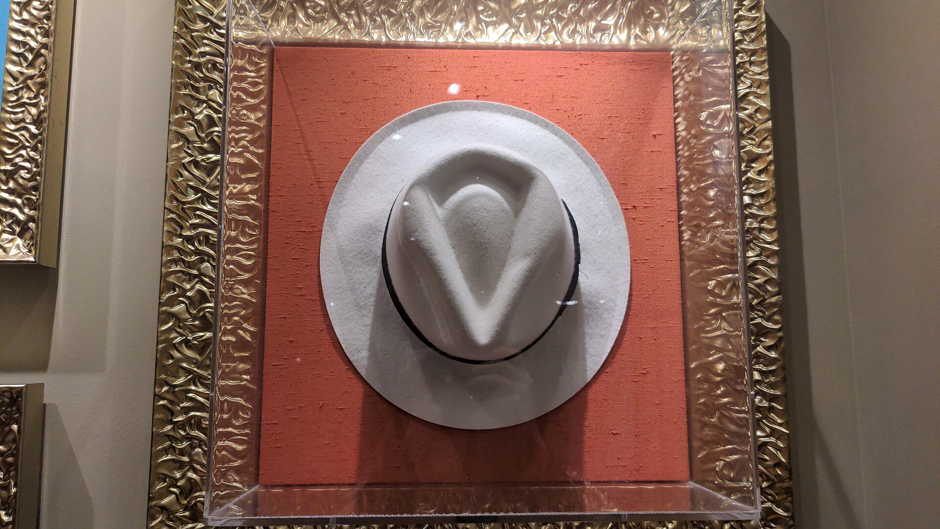 Chapéu fedora branco usado por Michael Jackson em "Smooth Criminal", exposto em uma moldura
