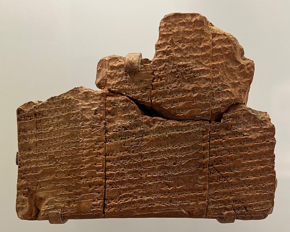 Tábua de argila quebrada com colunas de escrita cuneiforme, em vitrine